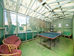 a screened porch with a ping pong table and chairs at Acclaim Pine Grove Holiday Park in Esperance