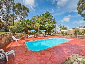 a swimming pool in a yard with chairs and a table at Acclaim Pine Grove Holiday Park in Esperance