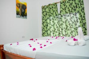 twee knuffeldieren op een bed met bloemen erop bij Daniel Zanzibar Hotel in Nungwi