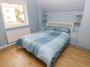 una camera da letto con un letto con lenzuola blu e una finestra di Old Orchard a Saundersfoot