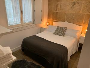 a bedroom with a bed with a black blanket and a window at Casa Cousiño Zona Monumental in Pontevedra