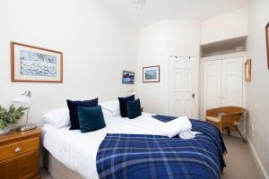 ein Schlafzimmer mit einem großen weißen Bett mit blauen Kissen in der Unterkunft Charming Hideaway in Edinburgh City Centre in Edinburgh