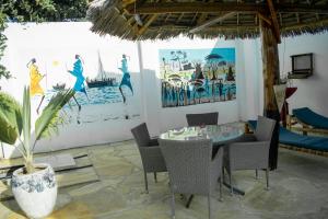 un comedor con mesa, sillas y una pintura en Daniel Zanzibar Hotel en Nungwi