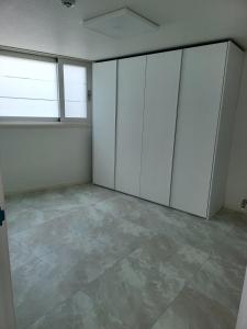 um quarto vazio com armários brancos e piso em azulejo em Storm Wind Poolvilla em Ulsan