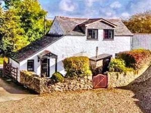 een schilderij van een wit huis met een rood hek bij Hallagenna Cottages in Bodmin