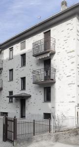 un edificio de ladrillo blanco con balcones y una valla en Casa Nina en Sondrio