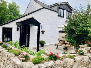 a white house with a bench in front of it at Hallagenna Cottages in Bodmin