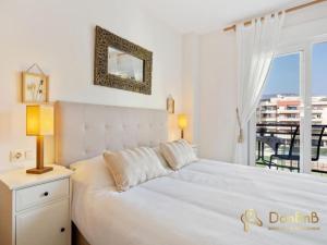 a bedroom with a large white bed and a balcony at Apartment with pool and private parking near Aqua Mijas in Fuengirola