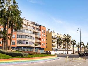 a building with palm trees in front of a street at Apartment with pool and private parking near Aqua Mijas in Fuengirola