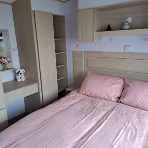a bedroom with a bed with pink sheets and shelves at CJ & Daisies Holiday Home in Prestatyn