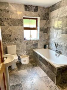 a bathroom with a tub and a toilet and a sink at Ballydonnellan in Westport