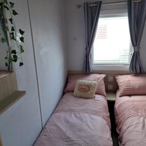 twee bedden in een kleine kamer met een raam bij CJ & Daisies Holiday Home in Prestatyn