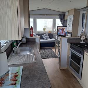 a kitchen with a sink and a living room at CJ & Daisies Holiday Home in Prestatyn
