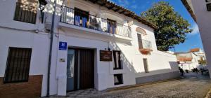 un edificio blanco con balcón en una calle en La posada de Alájar, en Alájar