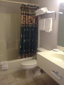 a bathroom with a toilet and a tub and a sink at Parkside Inn Bridgeview in Mackinaw City