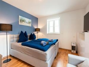 Haunsheim的住宿－Group Holiday Home in Haunsheim on the Danube，一间卧室配有一张带蓝色床单的床和一扇窗户。