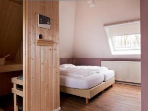 ein Schlafzimmer mit einem Bett und einer Holzwand in der Unterkunft Holiday home with sauna, outdoor spa in Earnewâld