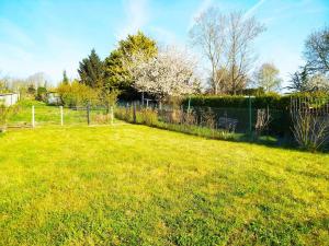 a field of green grass with a fence and trees at L'Embrun de la Baie de Somme in Saint-Valery-sur-Somme