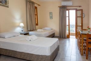 a hotel room with two beds and a table and chairs at Paradeisos in Kardamili