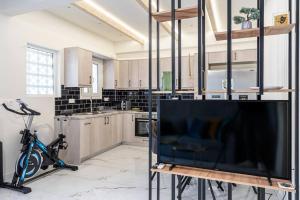 a kitchen with a flat screen tv and a bike in a room at Athens Flat with Gym Equipment 3 minutes to Metro in Athens +18 photos