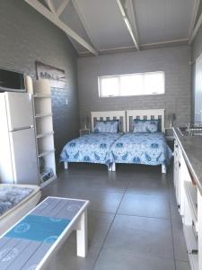1 dormitorio con 1 cama, nevera y mesa en Petite Selfcatering Accommodation Struisbaai SA, en Struisbaai