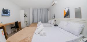 um quarto de hotel com duas camas e uma secretária em Hotel Rochedo AL em Penedo