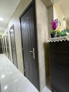 a row of black doors in a hallway with flowers at WAA Hostel in Dubai