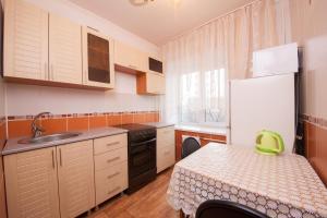 a small kitchen with a table and a refrigerator at Kvartirov Apartment at Surikova in Krasnoyarsk