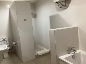 a white bathroom with a toilet and a sink at Adis Hotels Prime in Ibadan