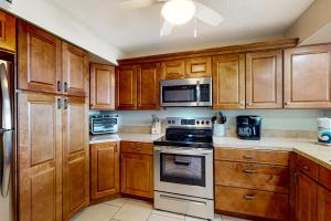 cocina con armarios de madera, fogones y microondas en Daytona Beach Living - Unit #504, en Daytona Beach