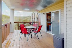 a porch with red chairs and a table on a deck at Woodpecker Lane Retreat in Branson