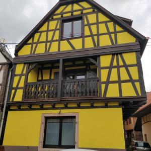 a yellow and black building with a balcony at Le Familial in Kintzheim