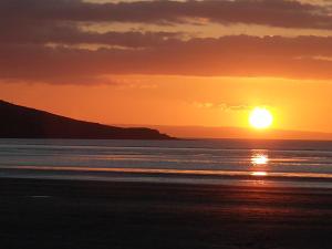 a sunset over the ocean with the sun in the sky at Sunnyside Lodge in Weston-super-Mare