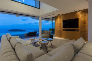 a living room with a large couch and a television at Villa Amylia Emerald, design excellence in Koh Samui