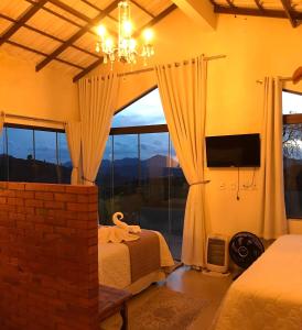 ein Schlafzimmer mit einem Bett und einem großen Fenster in der Unterkunft Mirante das Montanhas in Divisa