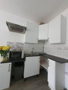 a kitchen with white cabinets and a microwave at Studio in London with free parking on premises in Thornton Heath