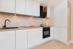 a kitchen with white cabinets and a sink at Beaufort Estate Apartment by Renters in Gdynia