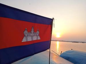 a flag on the back of a boat with the sunset at Tonle Mekong Homestay in Krong Kracheh