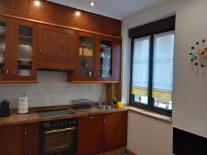 cocina con armarios de madera, fregadero y ventana en MenVal16, en Gijón