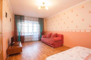 a living room with a red couch and a television at Kvartirov Apartment at Surikova in Krasnoyarsk