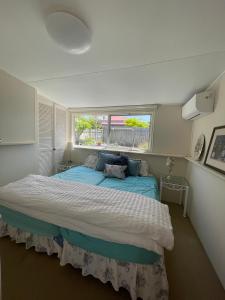 a bedroom with a large bed with a window at Beach view Rippleside Cottage in Geelong West