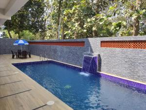 a swimming pool with a fountain in a backyard at Serene Sriperumbudur in Kāndūr