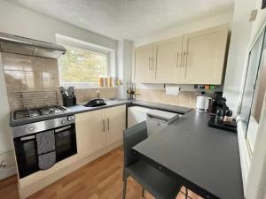 a kitchen with white cabinets and a black stove top oven at Cambridge Stay Cozy home with Wi-Fi, Parking Perfect for 2 in Cherry Hinton