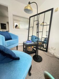 a living room with a blue couch and a mirror at Cambridge Stay Cozy home with Wi-Fi, Parking Perfect for 2 in Cherry Hinton