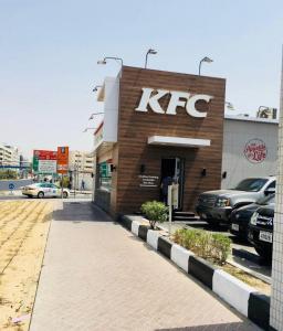 a kfc store with cars parked in a parking lot at WAA Hostel in Dubai