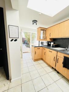 a kitchen with wooden cabinets and a tile floor at Lovely Dog Friendly, 3 Bed Home Sleeps 8, with Parking & Fenced Garden WORK CONTRACTOR LEISURE, JASPER in Cambridge
