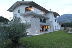 a large white house with a grass yard at B&B Relais Dolomiti in Bedollo