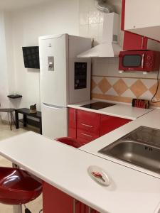 kuchnia z czerwonymi szafkami i białą lodówką w obiekcie FUENGIROLA APARTAMENT SUN&BEACH w mieście Fuengirola