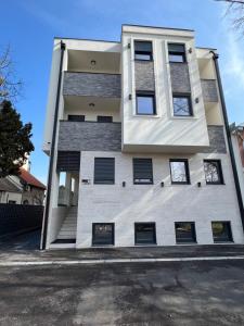 un grand bâtiment blanc avec des fenêtres sur une rue dans l'établissement Delete 8, à Novi Grad
