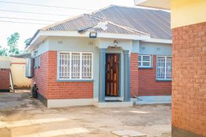 een rood bakstenen huis met een bruine deur bij Avon Garden Apartments Area 25 in Lilongwe